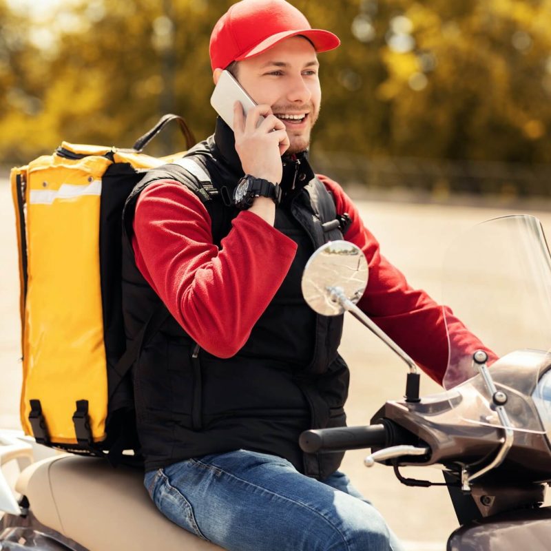 courier talking on mobile phone sitting on scooter in city 1.jpg