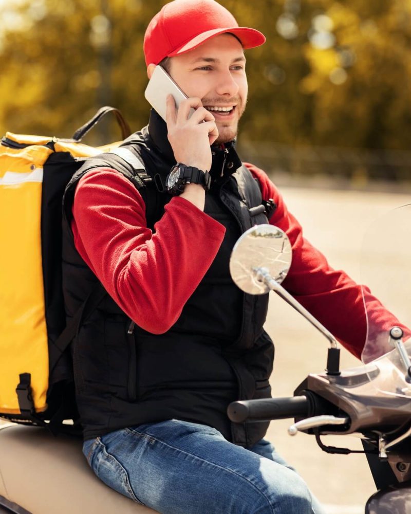 courier talking on mobile phone sitting on scooter in city 1.jpg