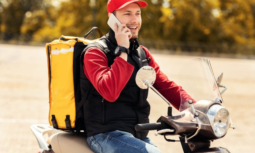 courier talking on mobile phone sitting on scooter in city 1.jpg