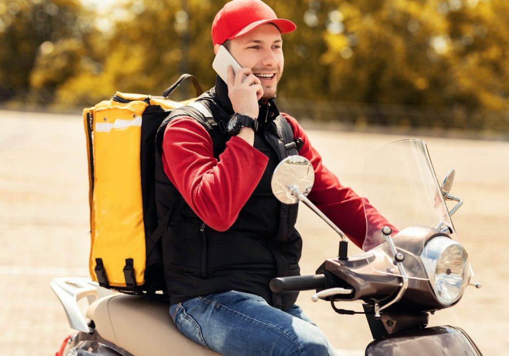 courier talking on mobile phone sitting on scooter in city 1.jpg